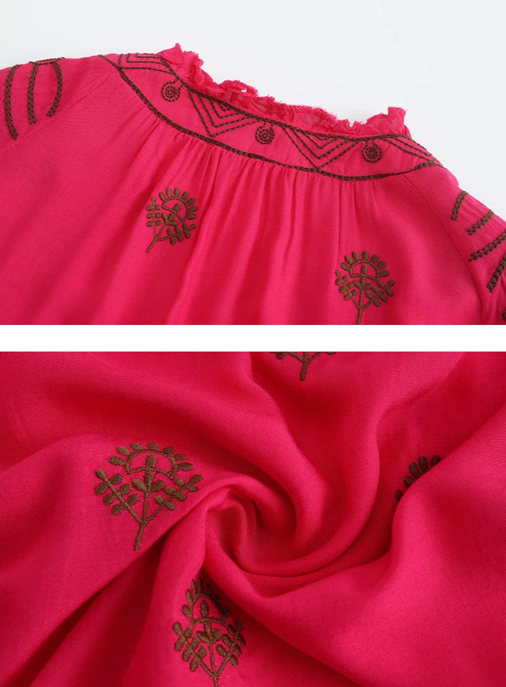 Close-up of a red dress with black floral embroidery on a white background