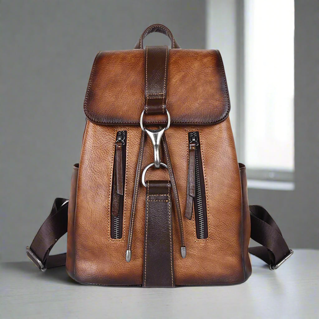Brown leather backpack with silver zippers on a white background