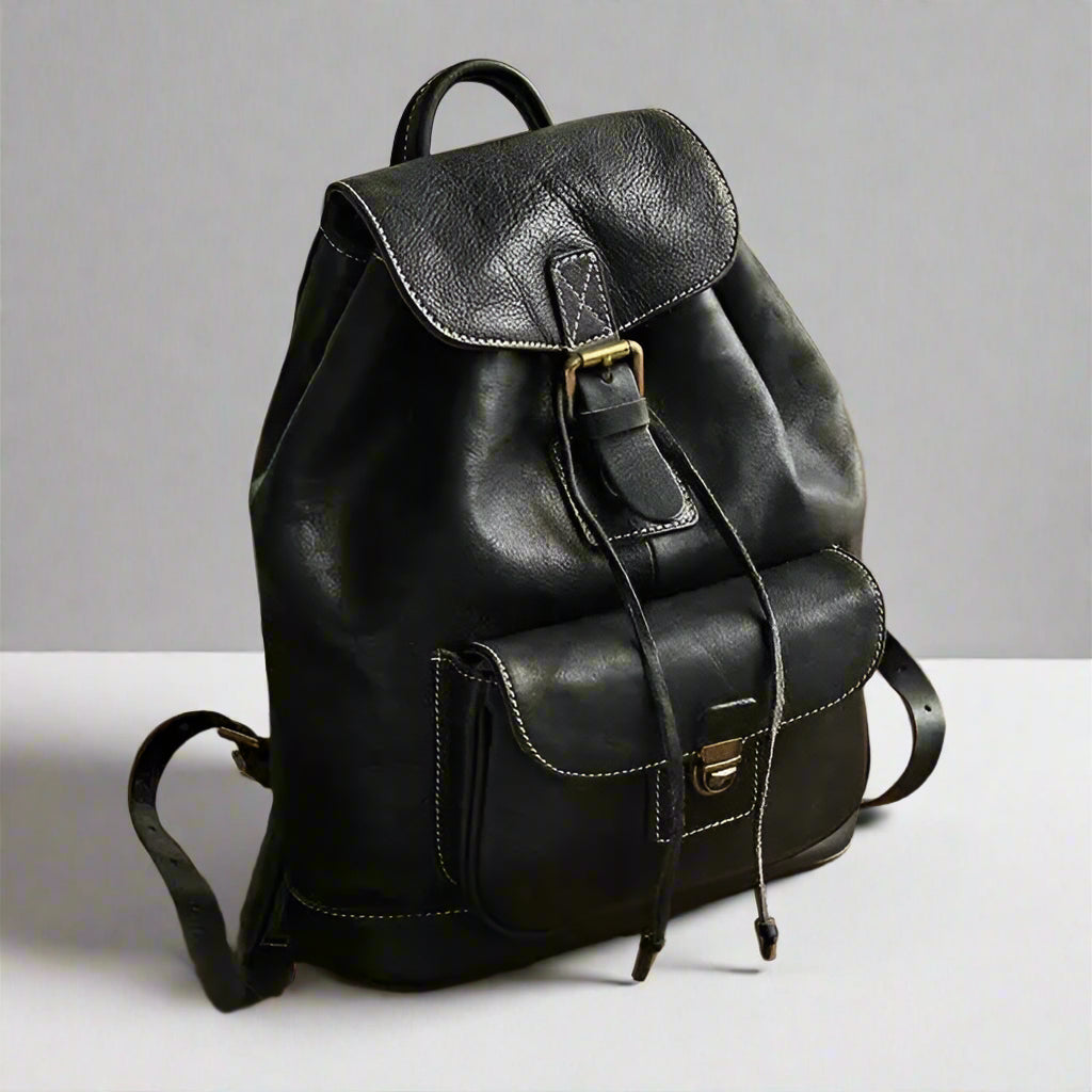 Black leather backpack on a wooden surface with a neutral background