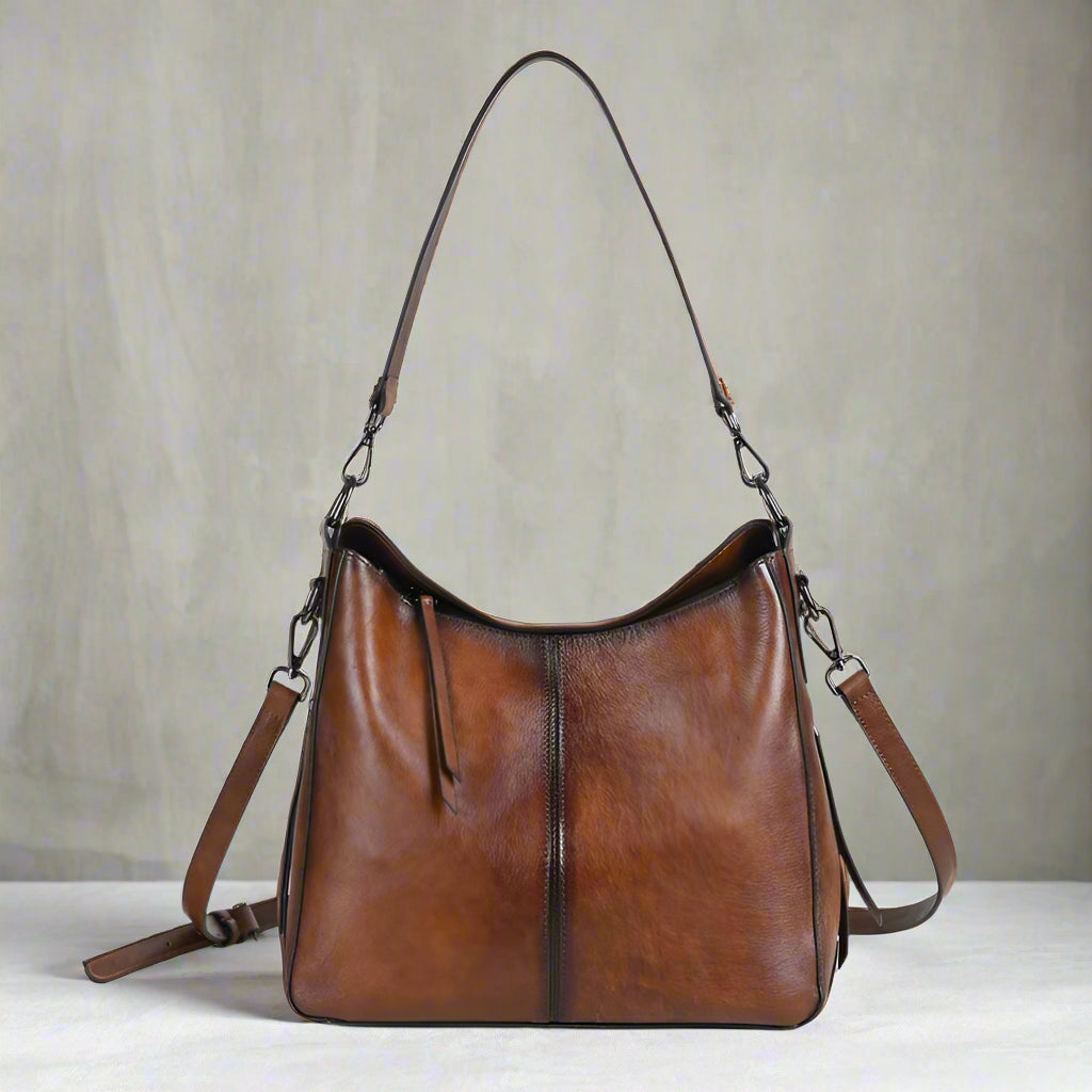 Brown leather handbag with shoulder straps on a white background