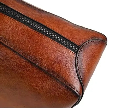 Close-up of a brown leather bag with a zipper on a white background