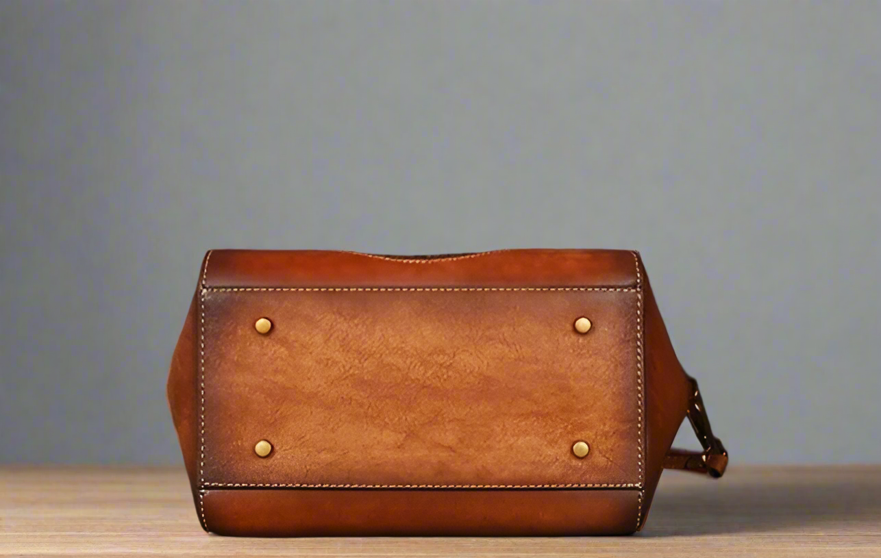 Brown leather bag with gold studs on a light background