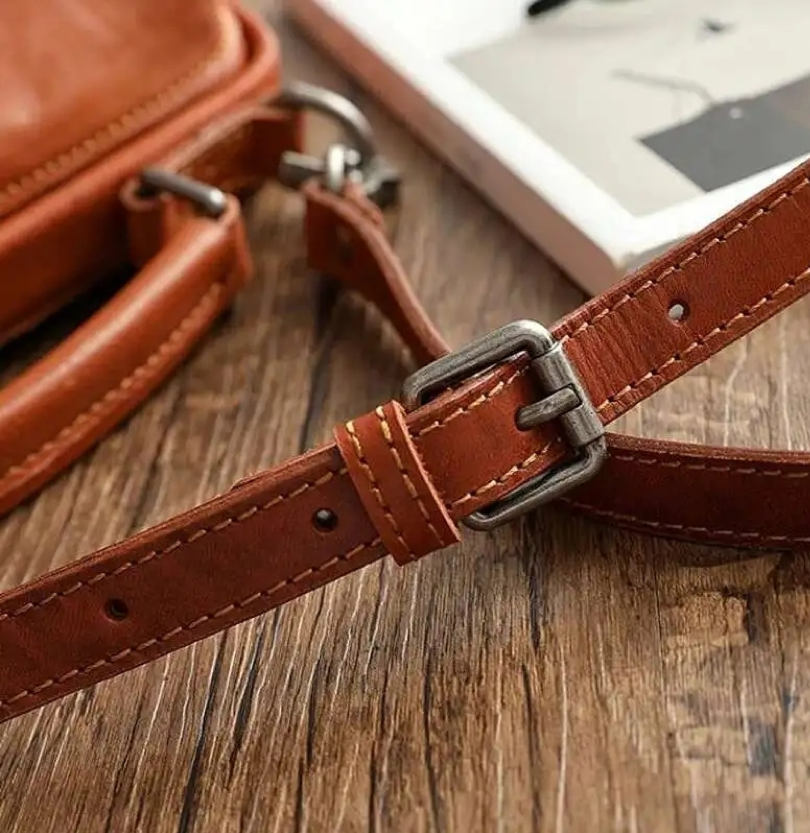 Brown leather strap with buckle on a wooden surface
