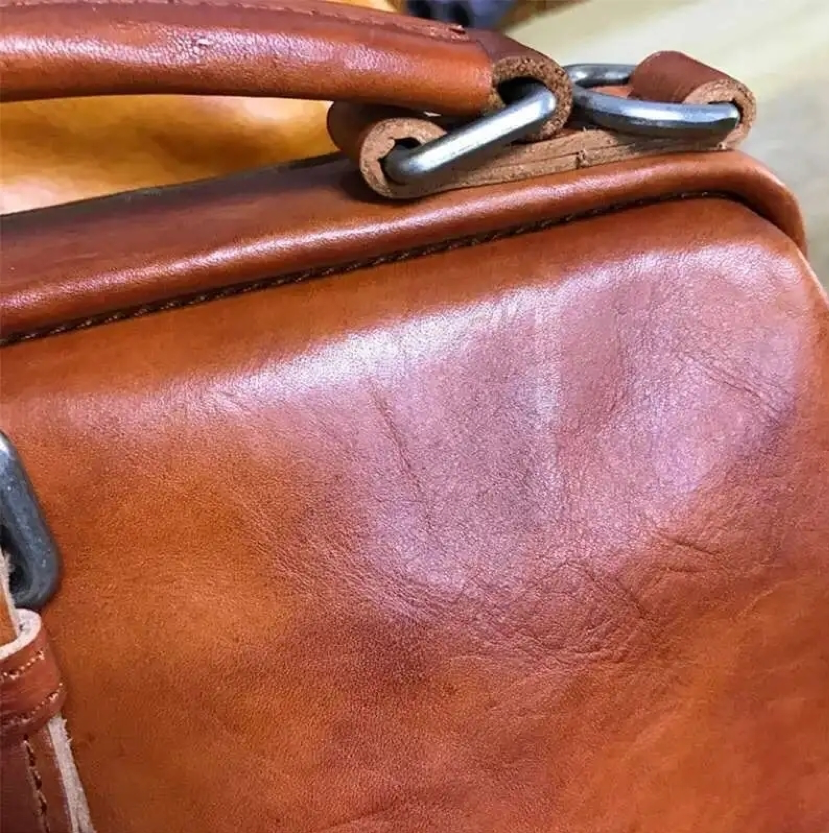 Close-up of a brown leather bag with metal hardware