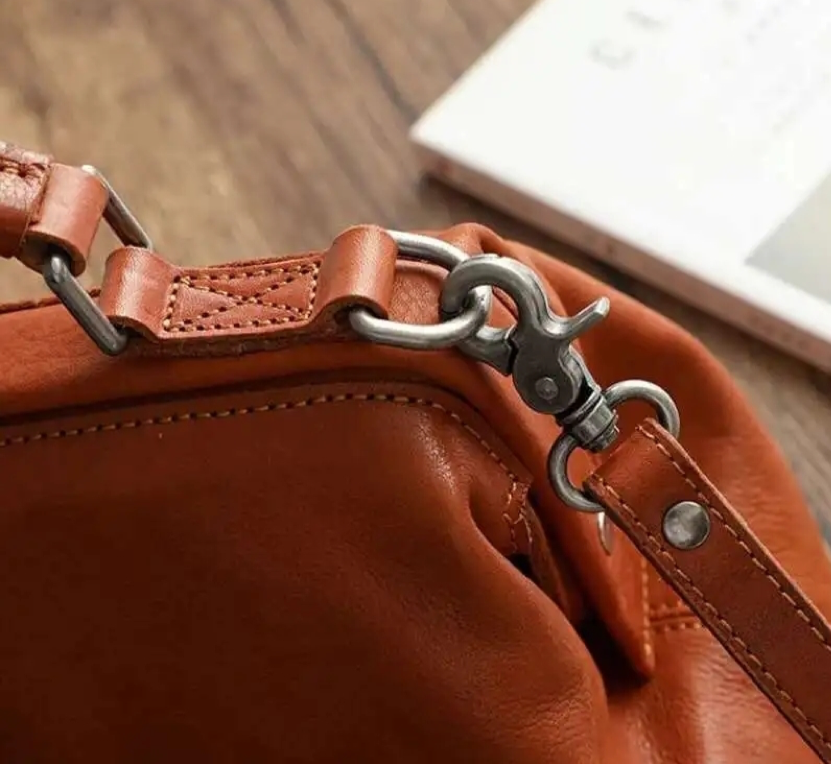 Close-up of a brown leather handbag with a metal clasp on a wooden surface.