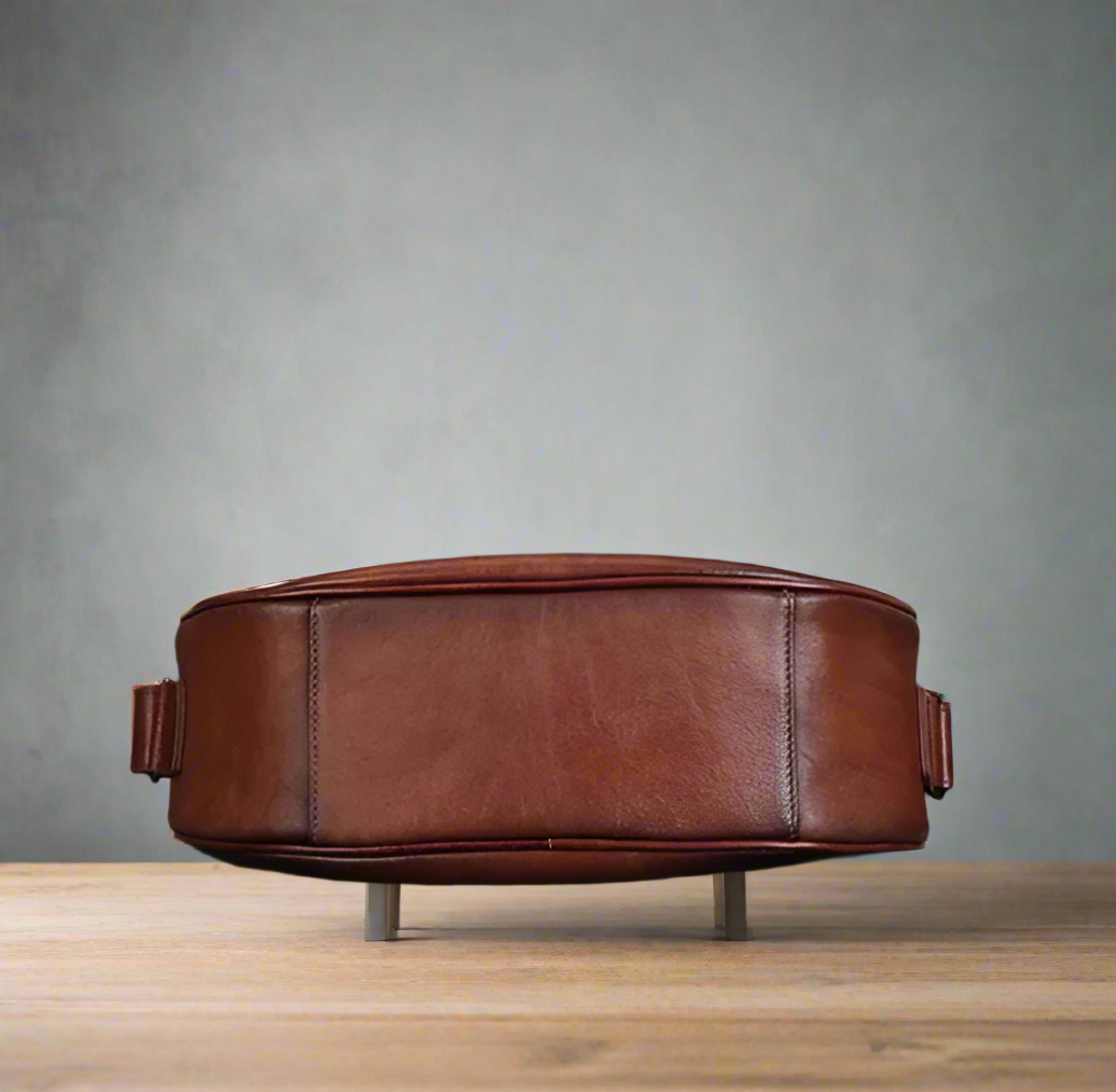 Brown leather crossbody bag on a gray background