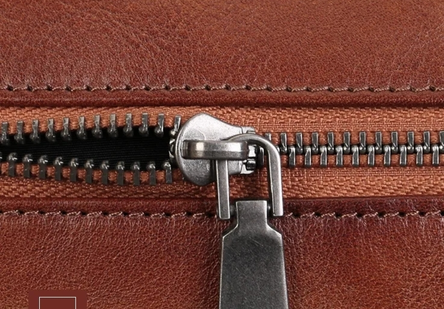 Close-up of a brown leather wallet with a zipper, showing texture and quality details.