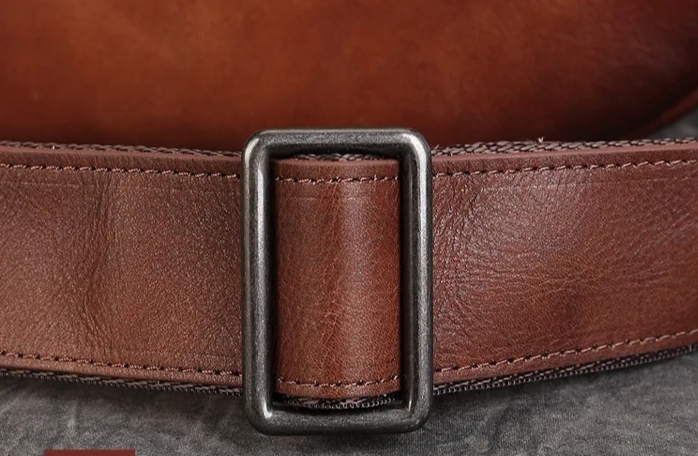 Brown leather belt with buckle on a dark background