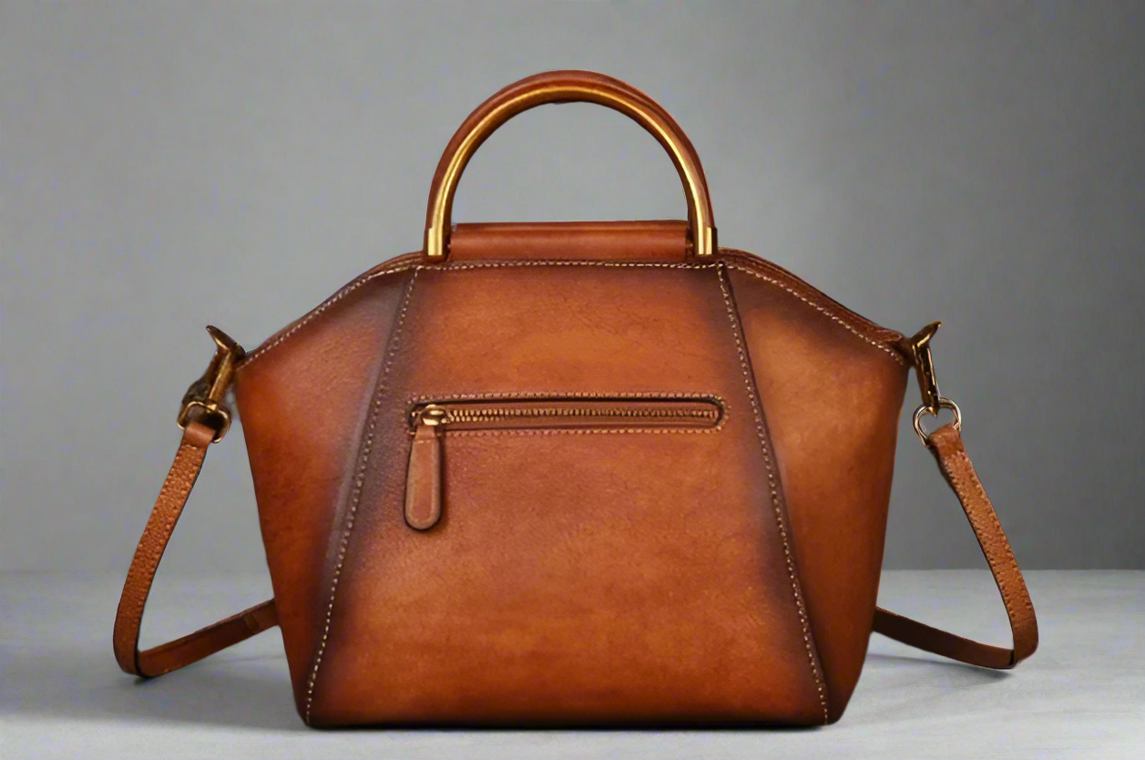 Brown leather handbag with gold accents on a light background