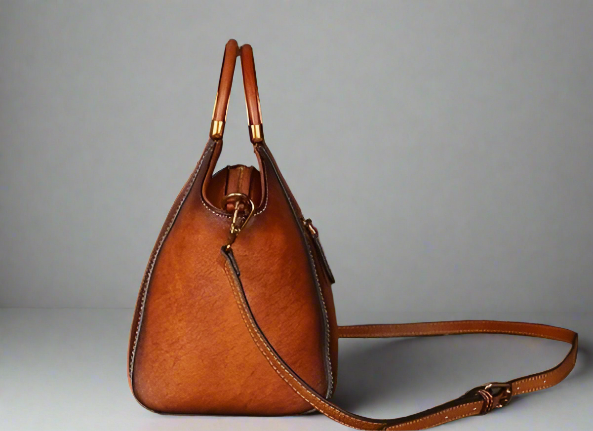 Brown leather handbag with gold accents on a light background