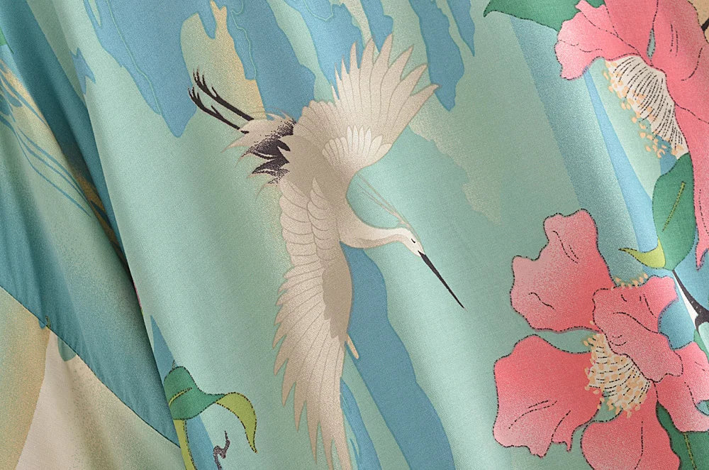 Decorative fabric with a crane and floral design on a green background