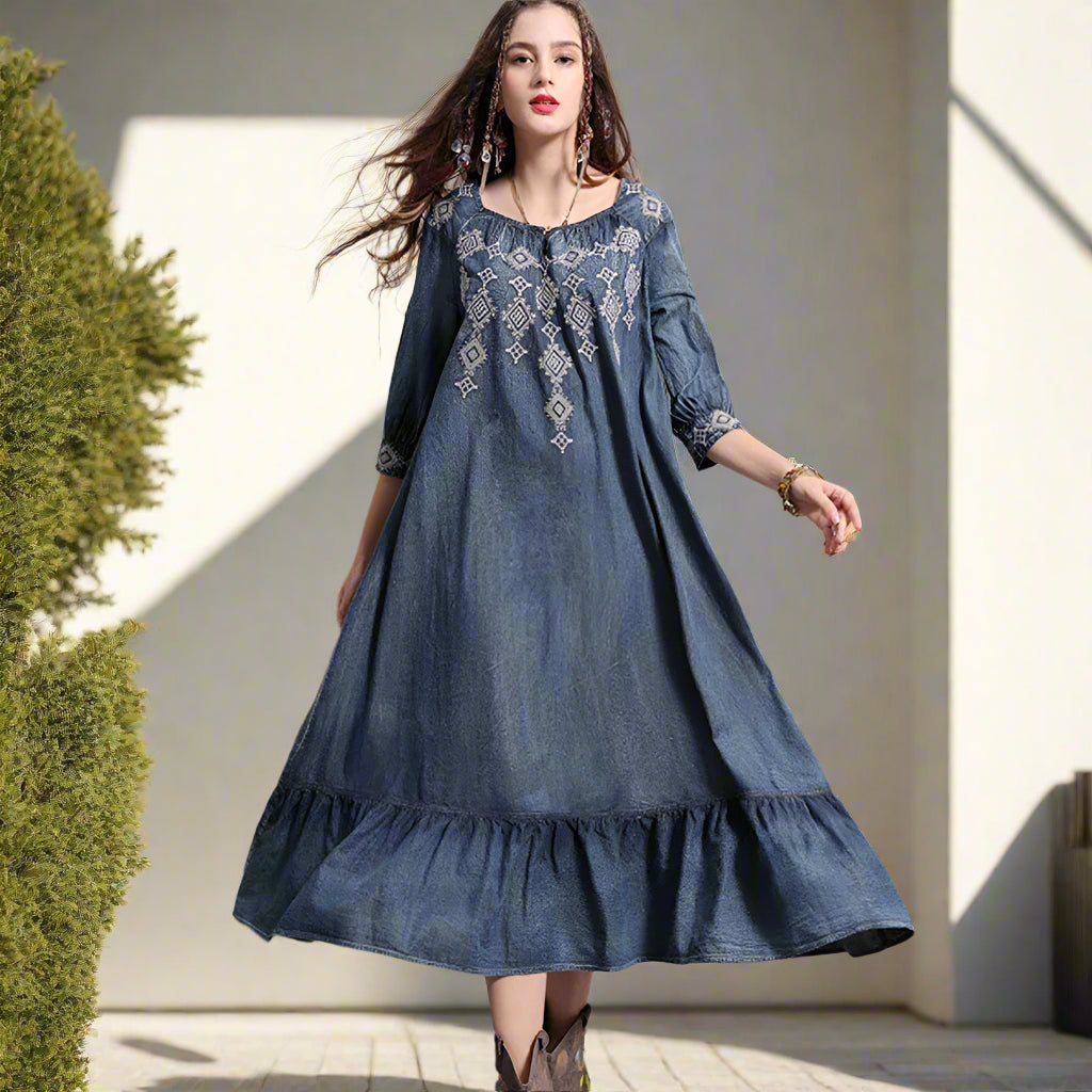 Woman wearing a blue embroidered dress against a backyard garden