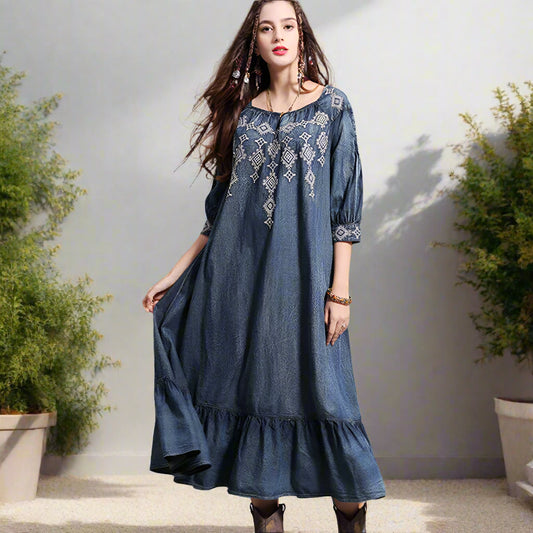 Woman wearing a blue embroidered dress against a backyard garden