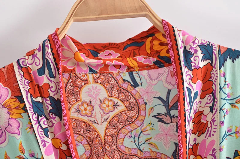 Colorful floral and paisley patterned fabric on a wooden hanger against a white background