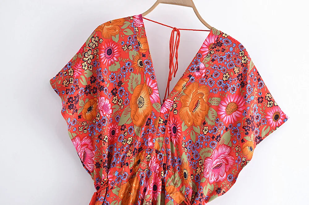 Colorful floral dress on a hanger against a white background