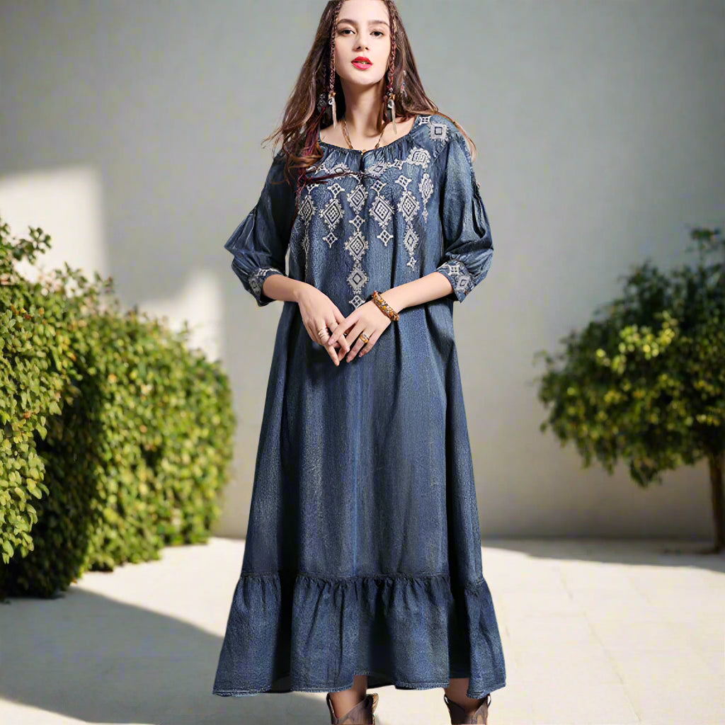 Woman wearing a blue embroidered dress against a backyard garden