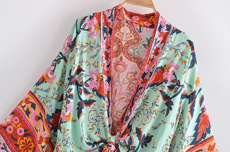 Colorful floral and paisley patterned garment on a hanger against a white background