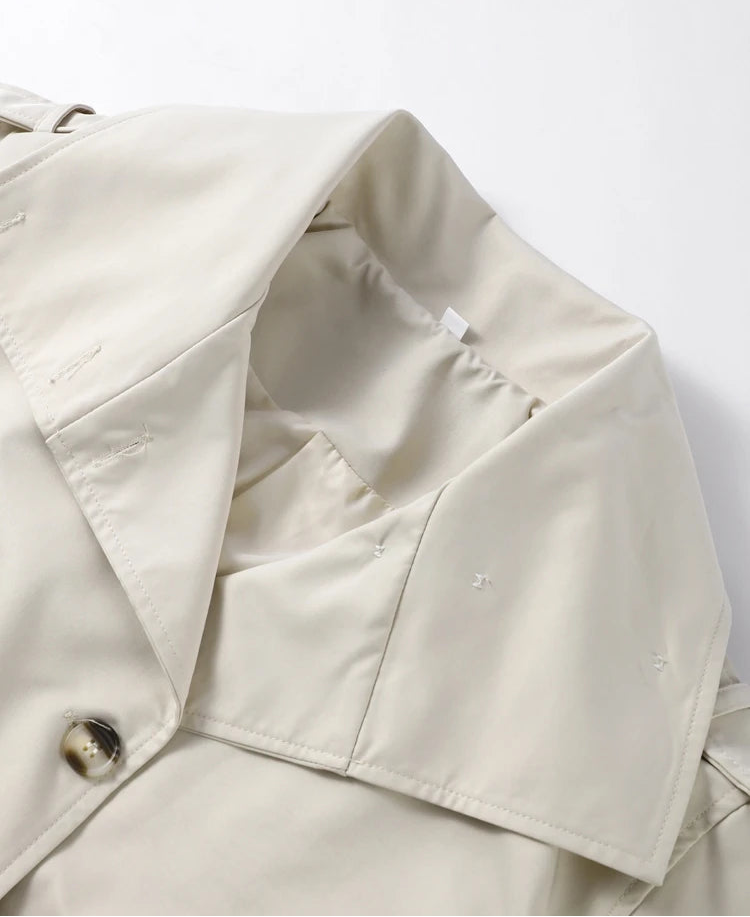 Close-up of a beige trench coat with a button on a white background