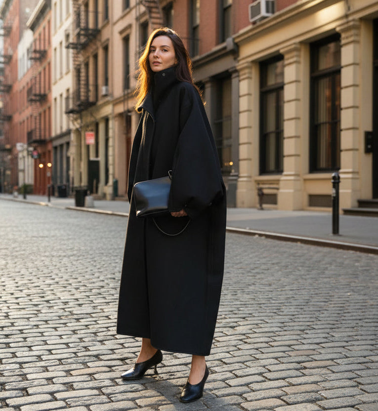 Woman in a long black coat holding a black handbag in new york street