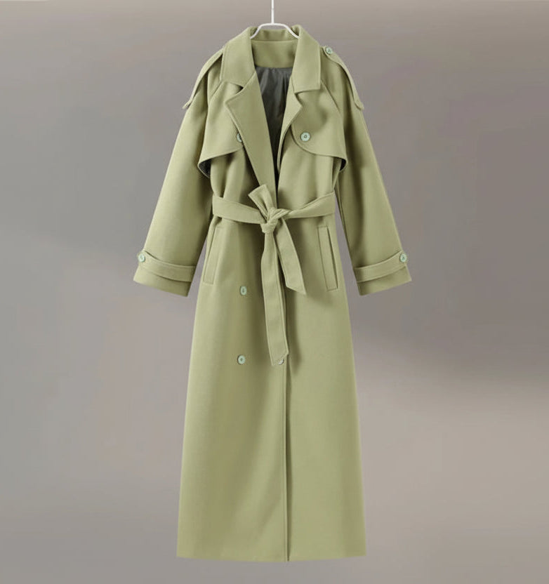 Green trench coat on a hanger against a neutral background