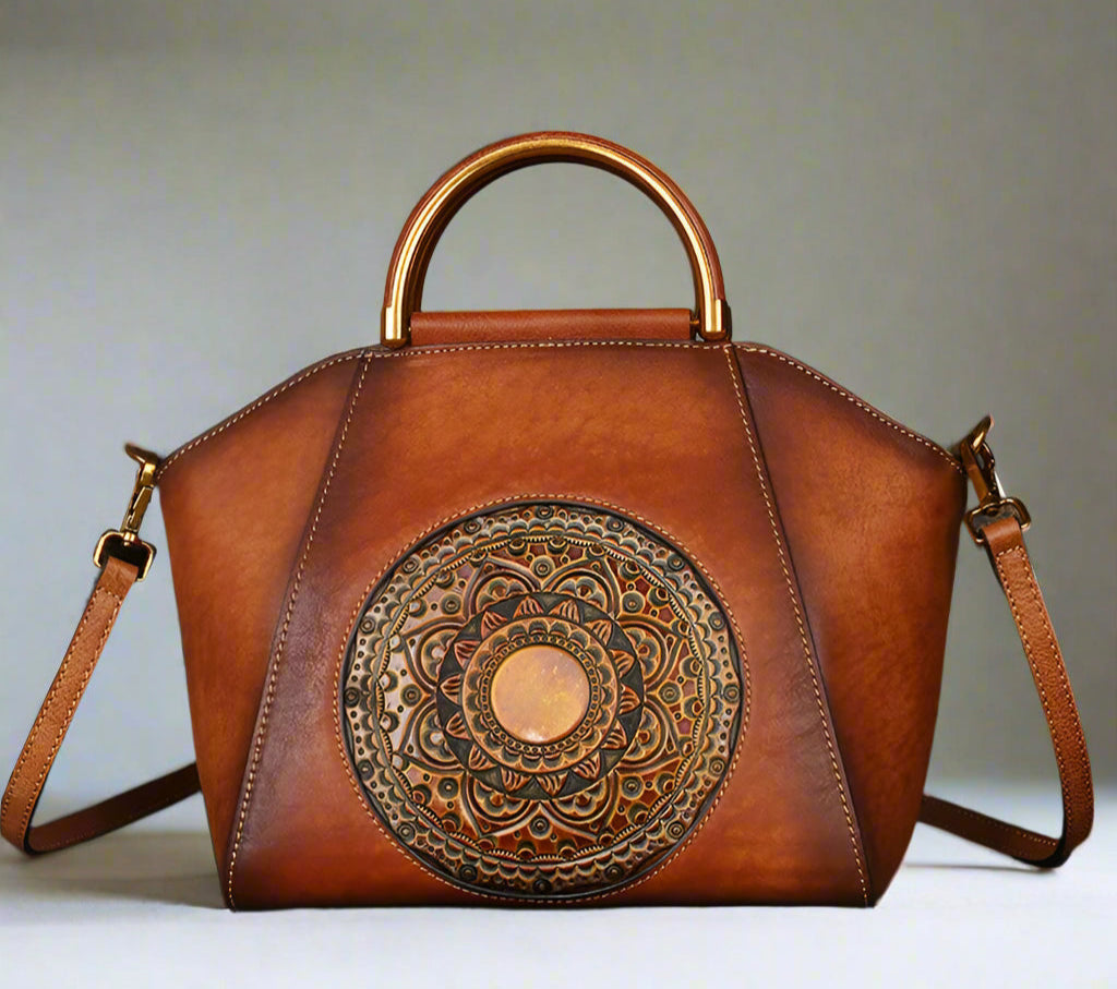 Brown leather handbag with decorative emblem on a light background