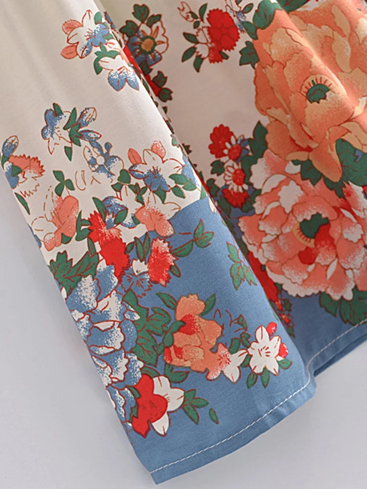 Close-up of floral-patterned fabric with a mix of red, orange, and blue colors on a white background.