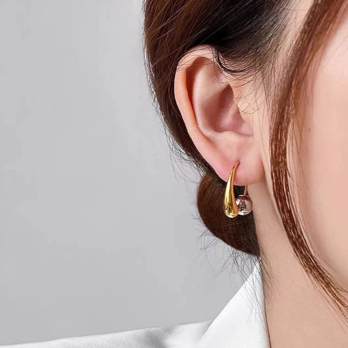 Gold hoop earrings worn by a person with a neutral background