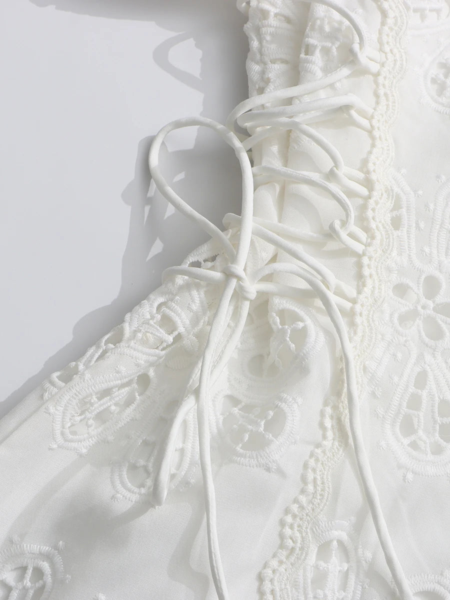 Close-up of a white lace wedding dress on a plain background