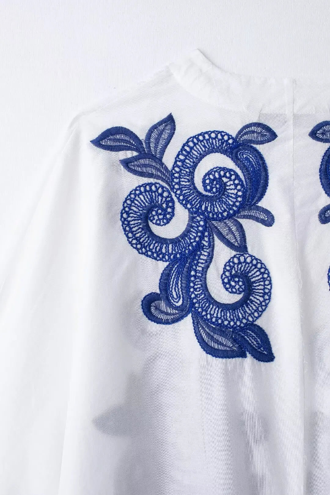 White garment with blue floral embroidery on a white background