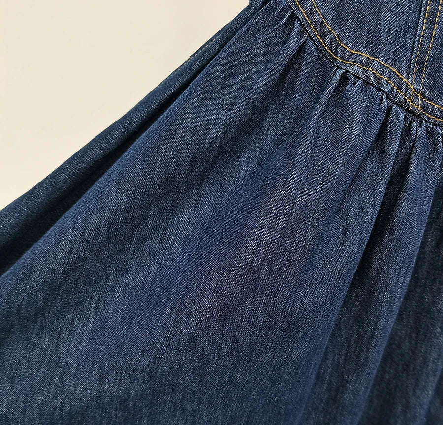 Close-up of a blue denim skirt with a beige background