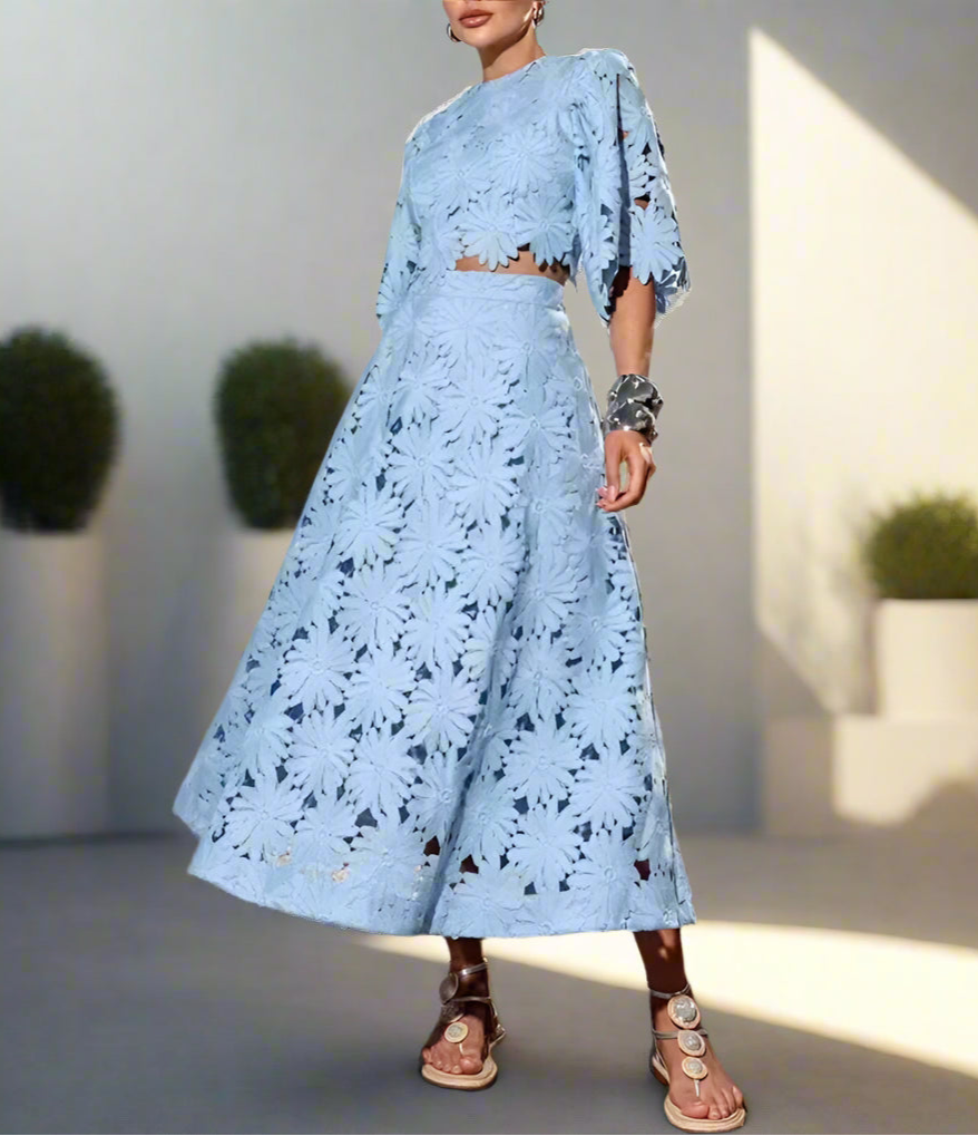 Woman in a light blue outfit set standing against backyard garden, sunny