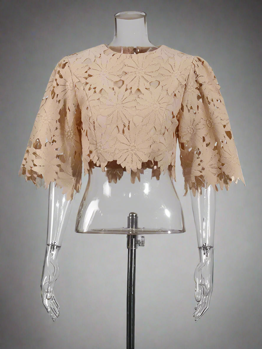 Beige lace top on a clear mannequin against a gray background
