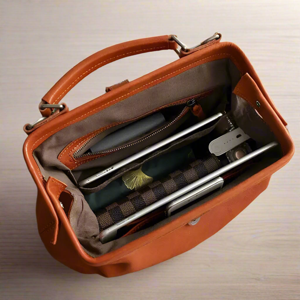 Brown leather briefcase open on a wooden surface with items inside