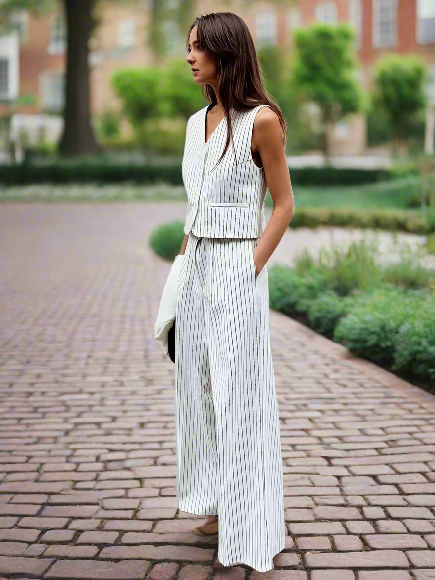 Woman wearing a white pinstripe suit standing against a backyard garden