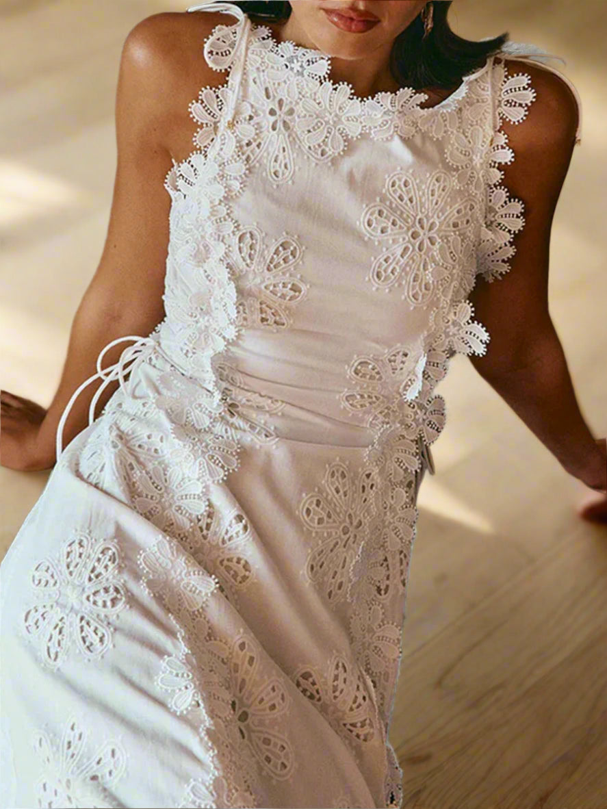White lace dress worn by a person sitting on a textured surface.