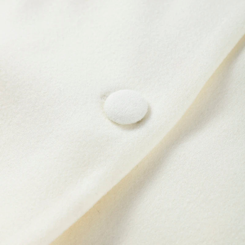 Close-up of a white button on beige fabric