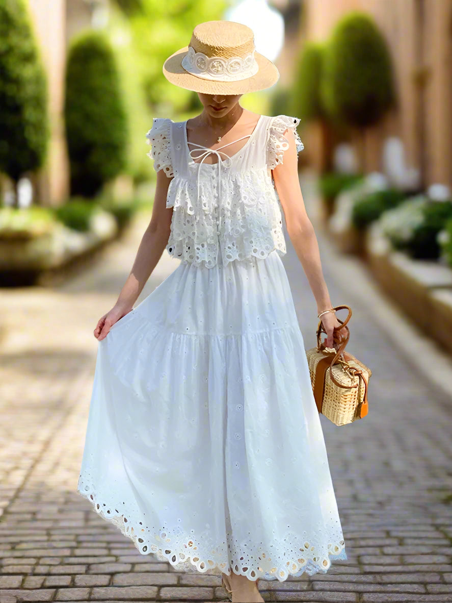 Woman in a white dress and straw hat standing in front of a backyard garden, sunny
