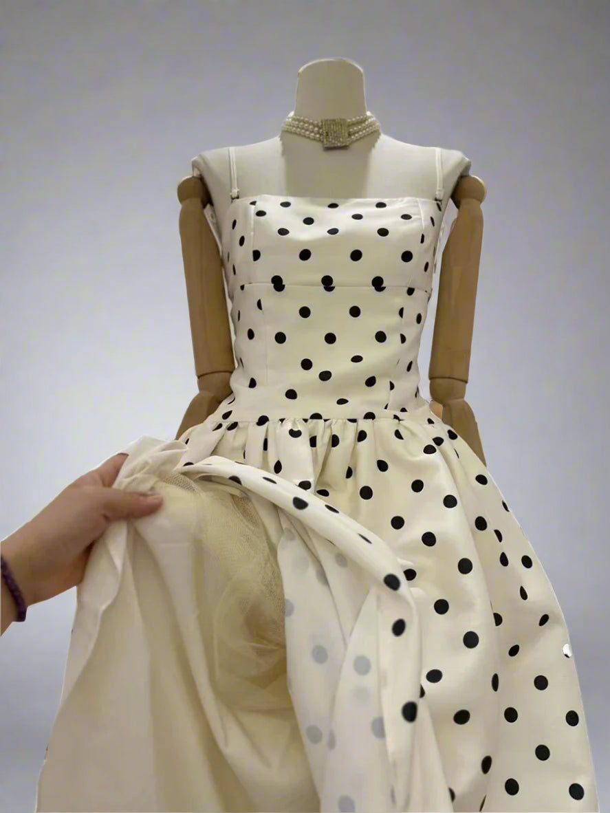White dress with black polka dots on a mannequin against a white background