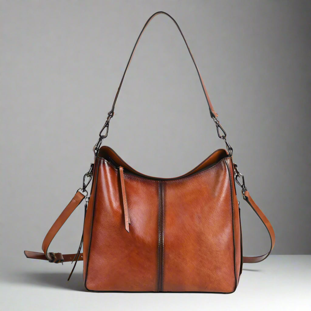 Brown leather handbag with a shoulder strap on a white background