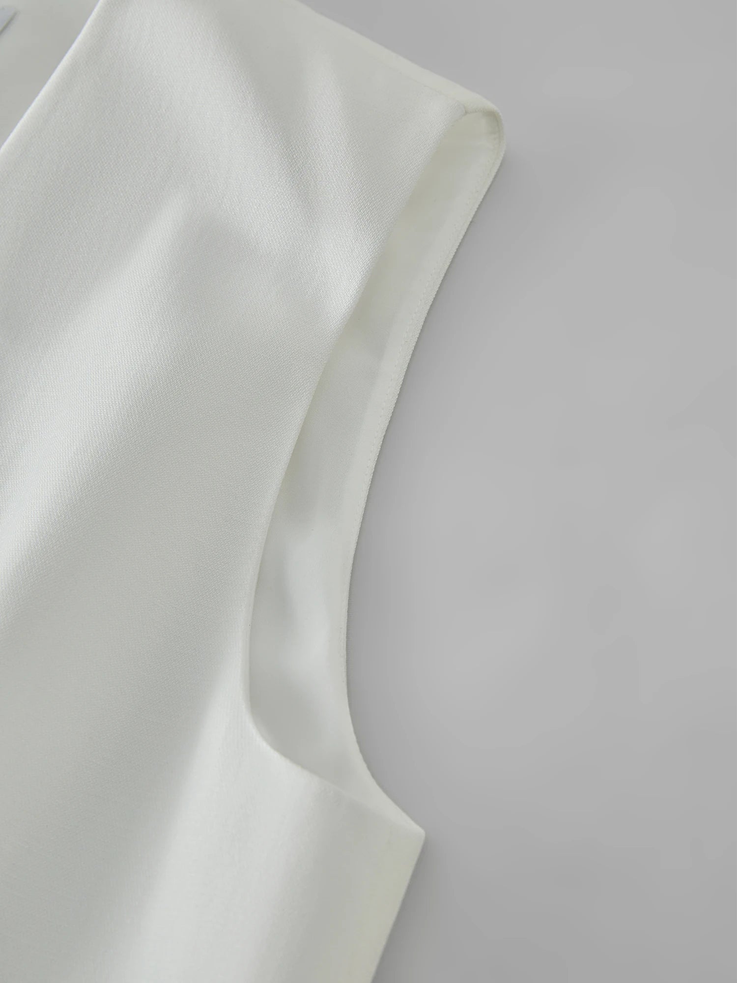 Close-up of a white fabric with a subtle texture on a light gray background