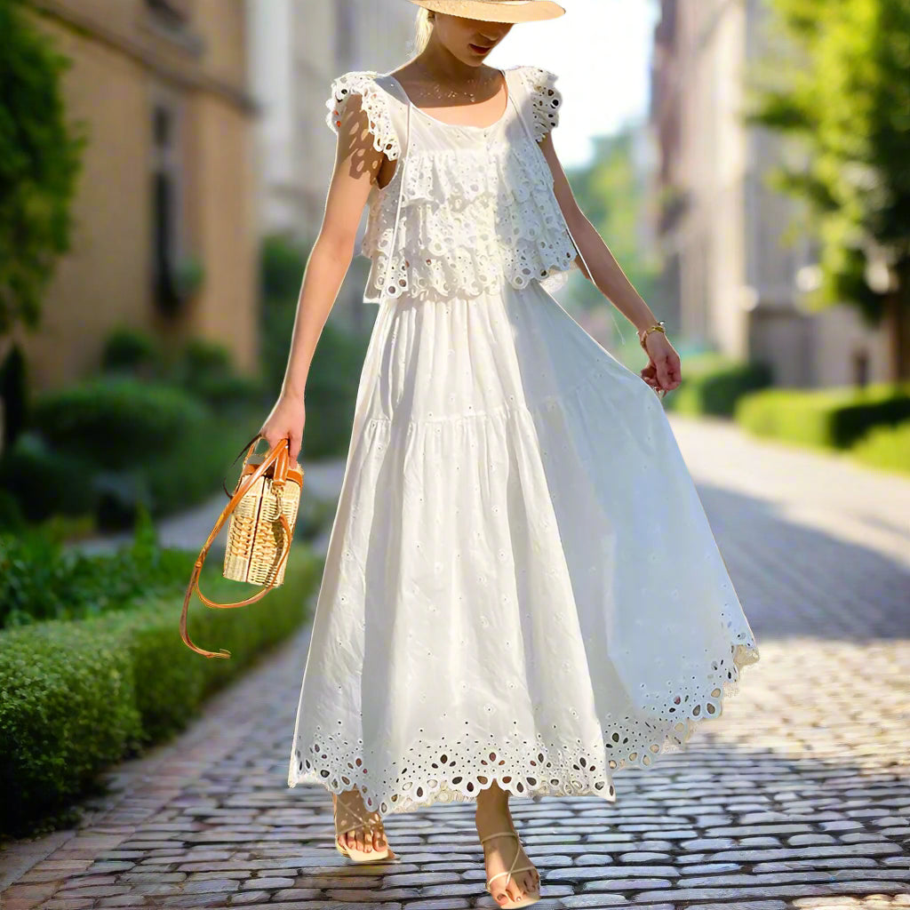 Woman in a white lace outfit standing outdoors with flowers and a backyard garden, sunny