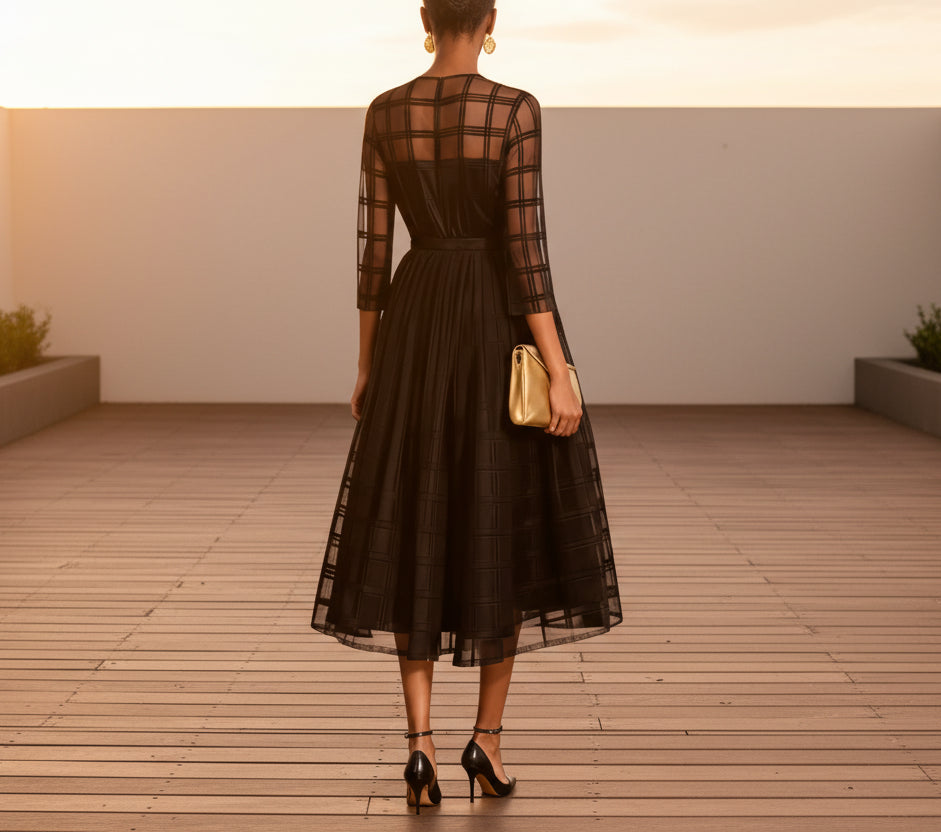 Black dress with sheer sleeves and a gold clutch on a ballroom