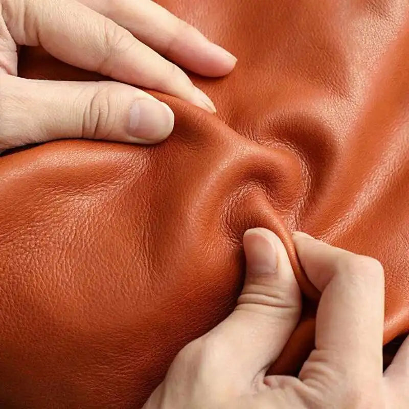 Close-up of hands inspecting brown leather