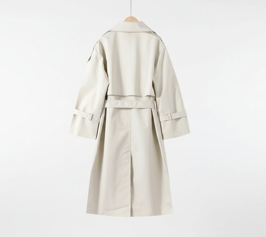White trench coat on a hanger against a neutral wall