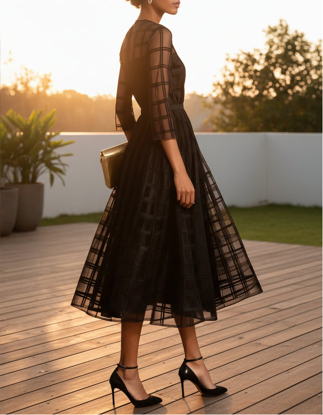 Black sheer dress with gold clutch on a minimal backyard