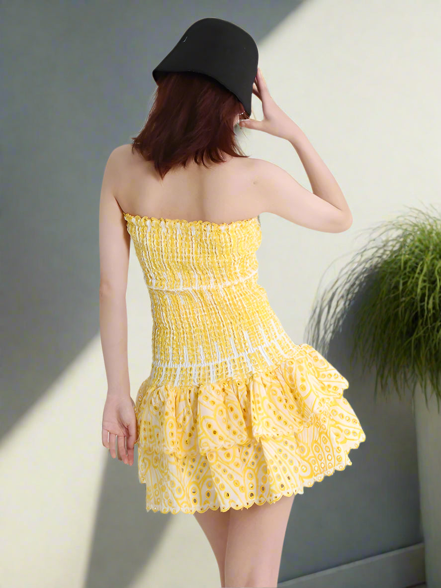 Woman wearing a yellow strapless dress with a white background