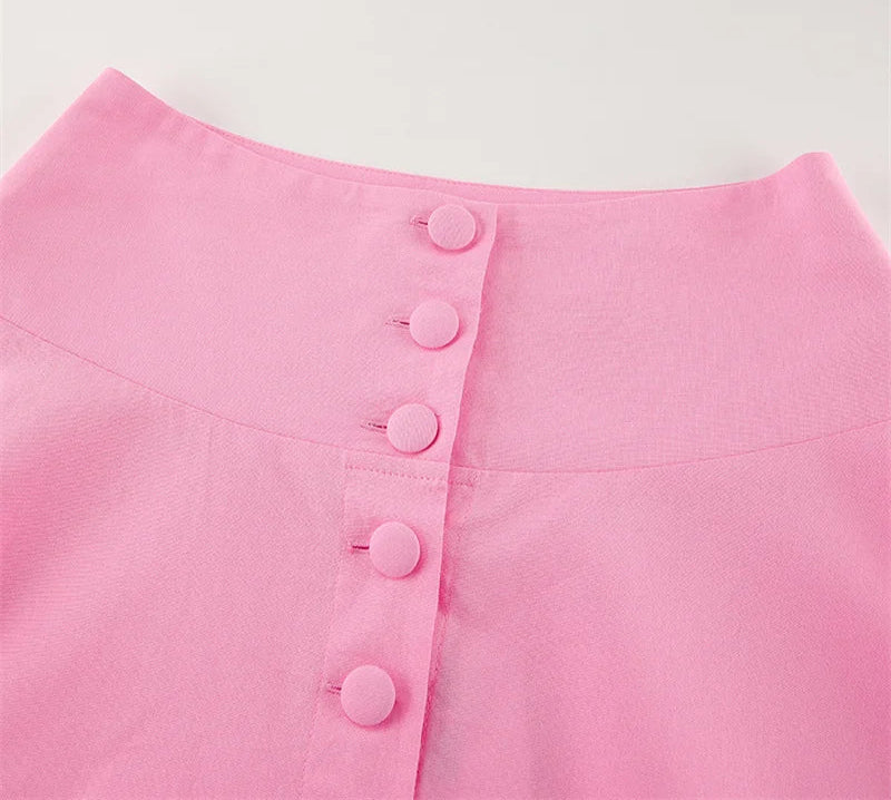 Close-up of a pink garment with buttons on a light gray background