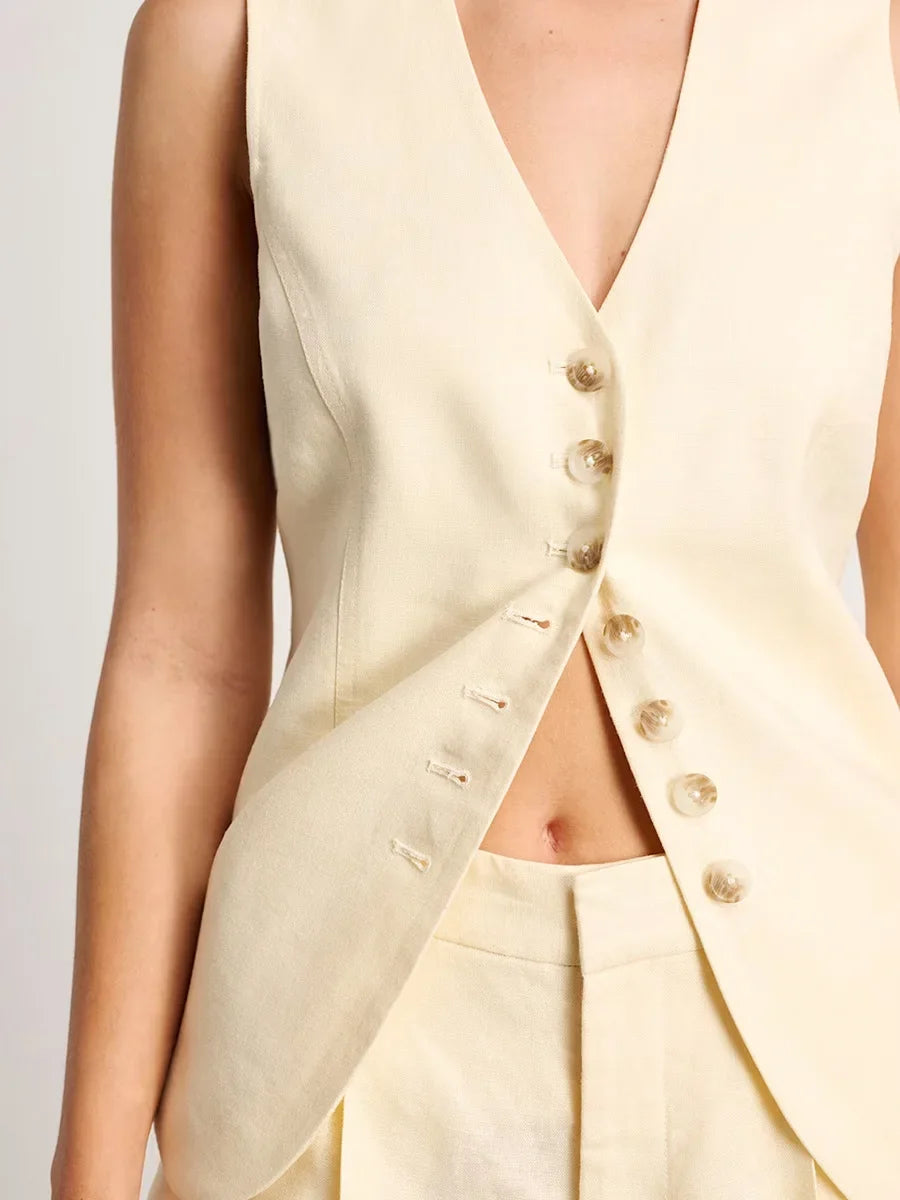 Light-colored sleeveless top with button details on a plain background