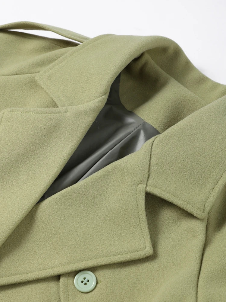 Close-up of a green coat with a button on a white background