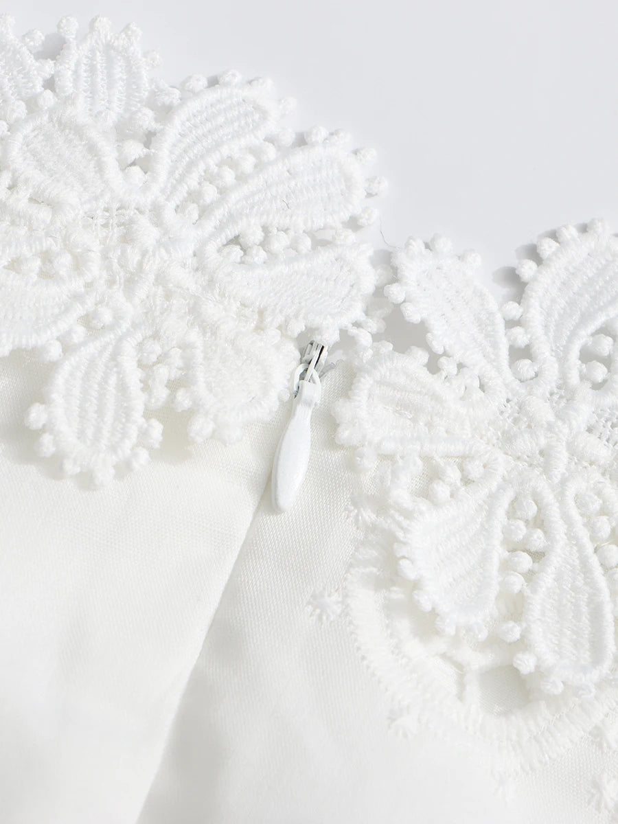 Close-up of a white lace garment with intricate detailing on a light gray background